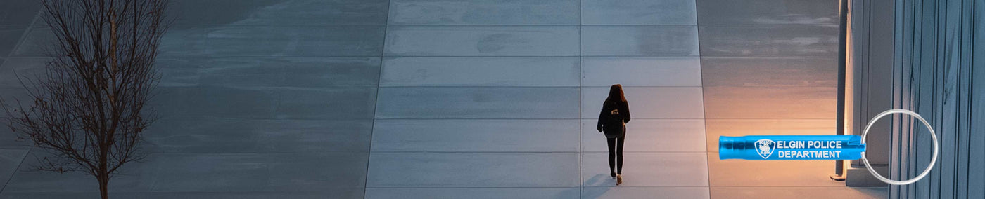 Woman walking alone in the evening with a safety whistle engraved with a police department logo