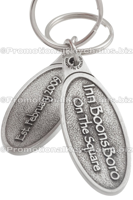 Both sides of an ovular genuine pewter keychain featuring "Inn BoonsBoro On The Square" embossed on the front and and the establishment date embossed on the back.