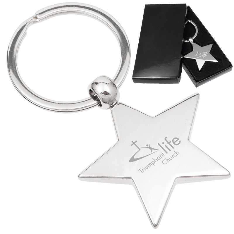 There are two images. On the right, a polished metal star-shaped keychain displayed in a black gift box. On the left is the same keychain with a logo clearly engraved in the center.