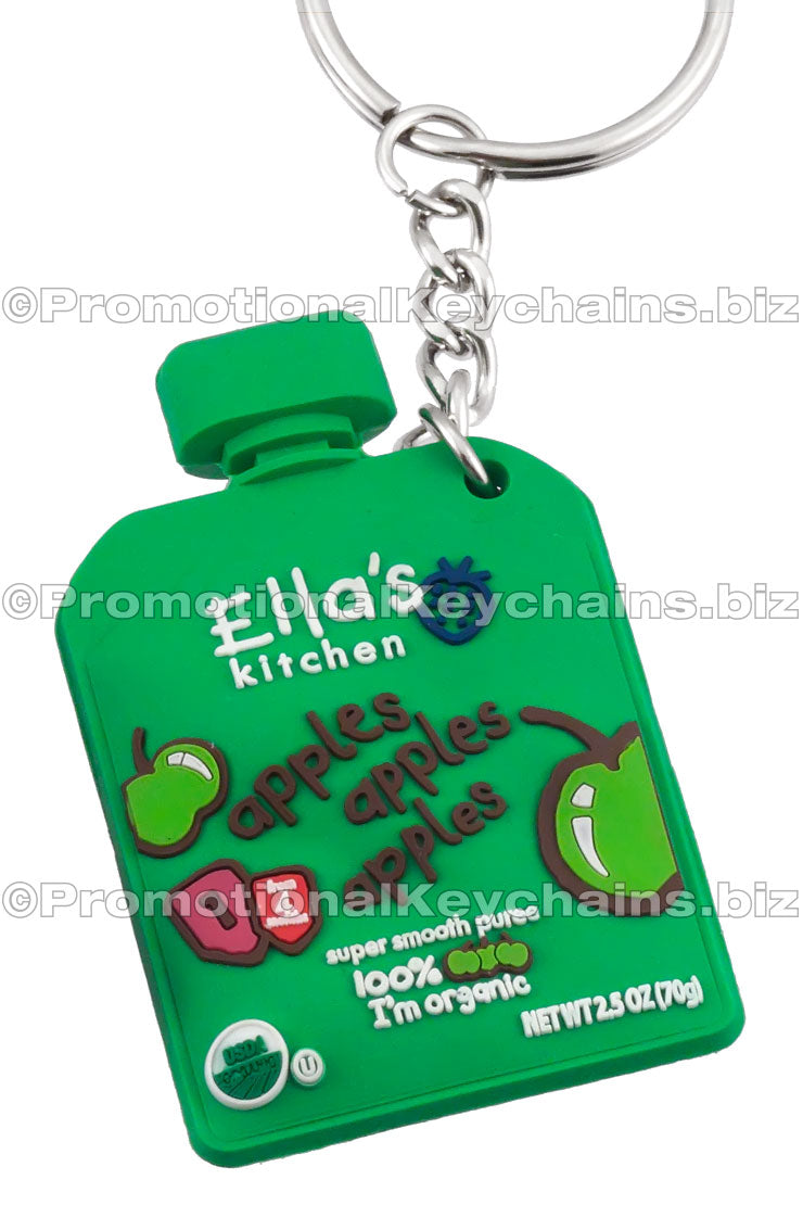 A green 3D PVC keychain shaped like a baby food pouch, labeled with "Ella's Kitchen" branding and cartoon granny smith apples.