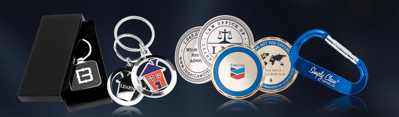 Collection of promotional items including keychains, coins and carabiners on a dark background.