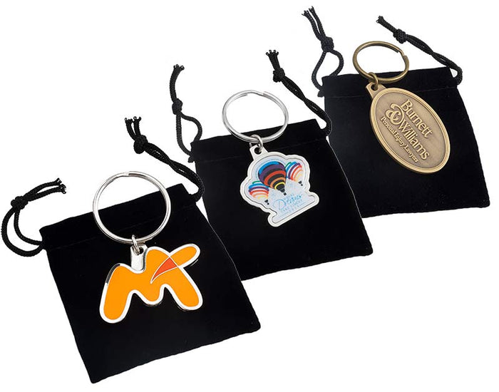 Three keychains in black drawstring bags with different designs.