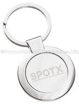 A polished, circular metal keychain featuring the "SPOTX" logo engraved in the center.