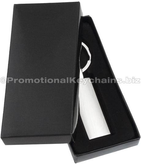 A rectangular polished metal keychain displayed in a black gift box.