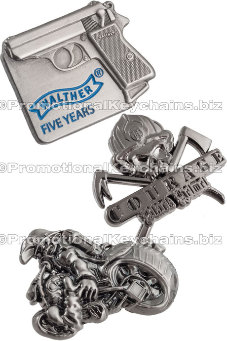 Group of 3D lapel pins showing antiqued nickel pins. Image included three 3D custom shaped lapel pins. One of a gun, one of a figure on a motorcycle and one of a skull in a fire helmet.