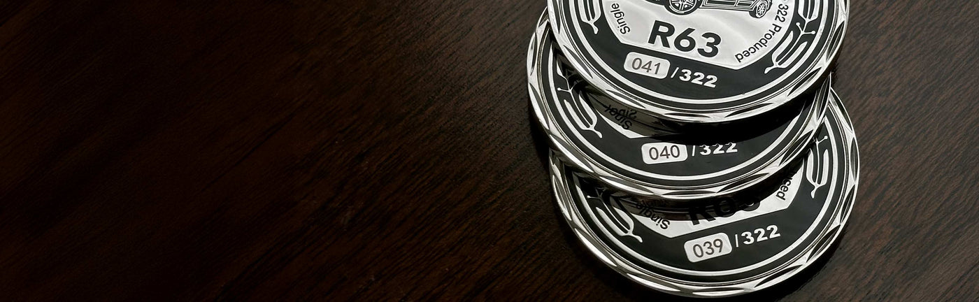 Stack of silver customized coins with visible sequential serialization numbers on a dark wooden surface.