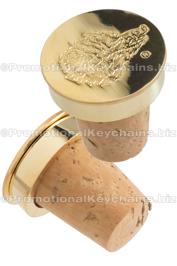 Two wine corks with polished gold metal tops, featuring an artistic boar head design die struck into the surface.