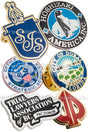 Group of hard enamel lapel pins showing different colors and shapes. Designs include a silver plated circle with penguin in center, another with USA eagle emblem, another design is shaped like a card spade with gold plating and red enamel.  