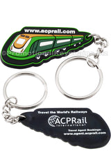 The front and back of a black PVC keychain. On one side, a green train with the website "acprail.com" above it. On the back side, the ACPRail International logo is screen printed in white along with other text.