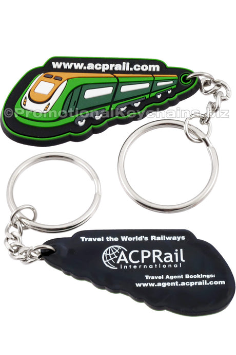 The front and back of a black PVC keychain. On one side, a green train with the website "acprail.com" above it. On the back side, the ACPRail International logo is screen printed in white along with other text.