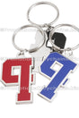 Two polished nickel keychains of the same design featuring the number "9" , one version in red enamel and the other in blue enamel. They are layered on top of the backside of  another of the same keychain, showing its smooth, shiny finish.