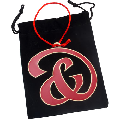 A custom-shaped holiday ornament with-enamel colors in an antiqued finish on a black velvet bag.