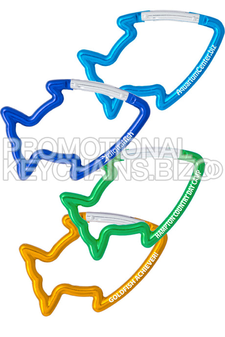 A light blue, dark blue, green and gold set of carabiners in the shape of a tropical fish, each laser engraved with various text. 