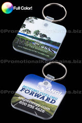 Pair of rounded square vinyl keychains with full color custom branding of Mansions at the Cascade and Moving Forward ANGI against a black background.