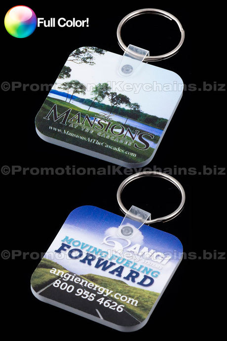 Pair of rounded square vinyl keychains with full color custom branding of Mansions at the Cascade and Moving Forward ANGI against a black background.