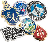 Layered image of hard enamel lapel pins showing different colors and shapes. Designs include a silver plated circle with penguin in center, another with USA eagle emblem, another design is shaped like a card spade with gold plating and red enamel.  