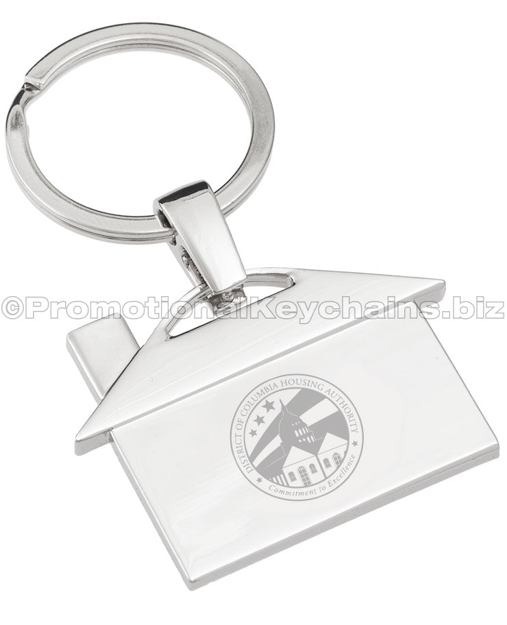A polished metal keychain that is shaped like a house, featuring an engraving of the logo for the District of Columbia Housing Authority.