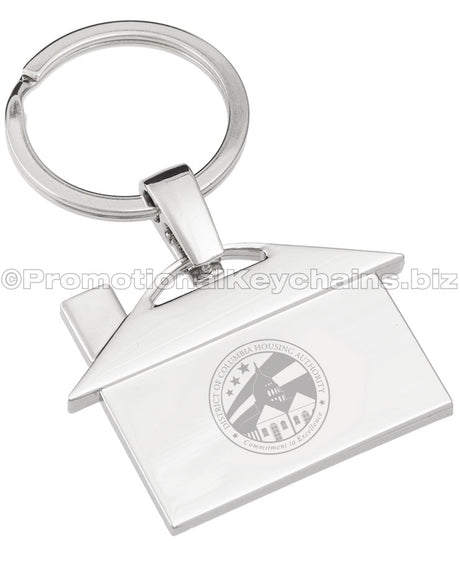 A polished metal keychain that is shaped like a house, featuring an engraving of the logo for the District of Columbia Housing Authority.